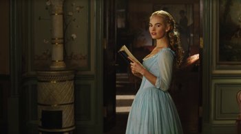 Movie still from “Cinderella” (2015), directed by Kenneth Branagh – A beautiful young lady in a blue dress holding an open book; Medium shot, Low angle