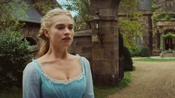 Movie still from “Cinderella” (2015), directed by Kenneth Branagh – A beautiful young lady wearing a blue dress standing in front of a stone wall; Close Up shot, Over the shoulder angle