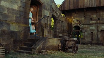 Movie still from “Cinderella” (2015), directed by Kenneth Branagh – A woman standing on the steps of an old building; Wide shot, Low angle