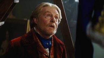 Movie still from “Cinderella” (2015), directed by Kenneth Branagh – An older man with long white hair wearing a red jacket; Close Up shot, Low angle