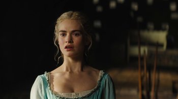 Movie still from “Cinderella” (2015), directed by Kenneth Branagh – A beautiful young woman with blonde hair standing next to a wall; Close Up shot, Over the shoulder angle