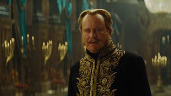 Movie still from “Cinderella” (2015), directed by Kenneth Branagh – A man in a black and gold jacket with long hair; Close Up shot, Over the shoulder angle