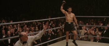 Movie still from “Cinderella Man” (2005), directed by Ron Howard – A man in a boxing ring holding a mitt; Medium shot, Low angle