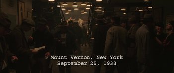 Movie still from “Cinderella Man” (2005), directed by Ron Howard – A group of people standing around in a room; Extreme Wide shot, High angle