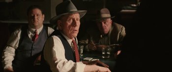 Movie still from “Cinderella Man” (2005), directed by Ron Howard – Two men sitting at a table in front of drinks; Medium shot, Over the shoulder angle