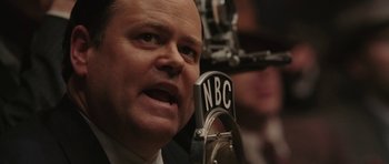 Movie still from “Cinderella Man” (2005), directed by Ron Howard – A man in a suit and tie talking into a microphone; Close Up shot, Low angle