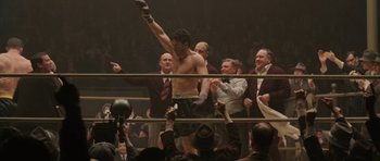 Movie still from “Cinderella Man” (2005), directed by Ron Howard – A man in a boxing ring with his hands raised; Medium shot, Low angle