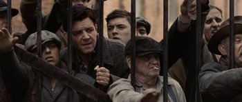 Movie still from “Cinderella Man” (2005), directed by Ron Howard – A group of men standing next to each other in front of a fence; Medium shot, Low angle