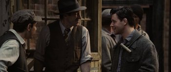 Movie still from “Cinderella Man” (2005), directed by Ron Howard – A man in a hat and vest talking to another man in a suit and tie; Medium shot, Over the shoulder angle
