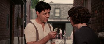 Movie still from “Cinderella Man” (2005), directed by Ron Howard – A man holding a bunch of money in his hands; Medium shot, Over the shoulder angle