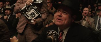 Movie still from “Cinderella Man” (2005), directed by Ron Howard – A man in a suit and a hat is holding a camera; Close Up shot, Over the shoulder angle