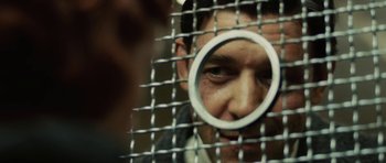 Movie still from “Cinderella Man” (2005), directed by Ron Howard – A person looking through a hole in a metal fence; Extreme Close Up shot, Over the shoulder angle