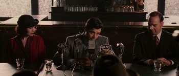 Movie still from “Cinderella Man” (2005), directed by Ron Howard – A man sitting at a table in front of microphones; Medium shot, Over the shoulder angle