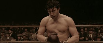 Movie still from “Cinderella Man” (2005), directed by Ron Howard – A shirtless man in a boxing ring holding a boxing mitts; Medium shot, Low angle