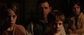 Movie still from “Cinderella Man” (2005), directed by Ron Howard – A man and a boy are standing in a dark room; Close Up shot, Over the shoulder angle