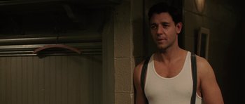 Movie still from “Cinderella Man” (2005), directed by Ron Howard – A man in a white tank top standing next to a brick wall; Medium shot, Over the shoulder angle
