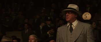 Movie still from “Cinderella Man” (2005), directed by Ron Howard – A man in a suit and hat standing in front of a group of people; Close Up shot, Over the shoulder angle