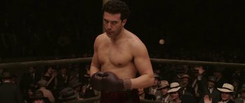 Movie still from “Cinderella Man” (2005), directed by Ron Howard – A man in a boxing ring wearing a black boxing glove; Medium shot, Low angle