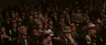 Movie still from “Cinderella Man” (2005), directed by Ron Howard – A group of men in suits and hats singing in a theater; Wide shot, High angle