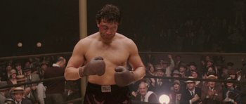 Movie still from “Cinderella Man” (2005), directed by Ron Howard – A man wearing boxing gloves in a boxing ring; Medium shot, Low angle