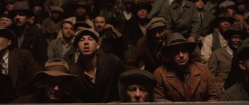 Movie still from “Cinderella Man” (2005), directed by Ron Howard – A group of men in hats sitting in front of a crowd; Medium shot, Low angle