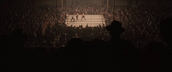 Movie still from “Cinderella Man” (2005), directed by Ron Howard – A crowd of people watching a boxing match in a boxing ring; Extreme Wide shot, High angle