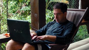 Movie still from “Citizenfour” (2014), directed by Laura Poitras – A man sitting in a chair using a lap top computer; Close Up shot, High angle