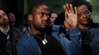 Movie still from “Citizenfour” (2014), directed by Laura Poitras – A man in a crowd of people holding his hand up; Close Up shot, Low angle