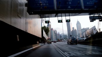 Movie still from “Citizenfour” (2014), directed by Laura Poitras – Cars driving on a highway with a view of a city; Extreme Wide shot, Low angle