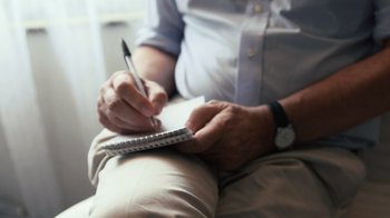 Movie still from “Citizenfour” (2014), directed by Laura Poitras – An older man writing on a notepad with a pen; Extreme Close Up shot, High angle