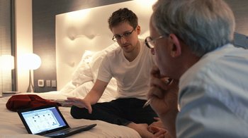 Movie still from “Citizenfour” (2014), directed by Laura Poitras – Two men sitting on a bed looking at a computer screen; Medium shot, High angle