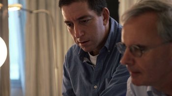 Movie still from “Citizenfour” (2014), directed by Laura Poitras – A man sitting next to another man while looking at a computer screen; Close Up shot, High angle