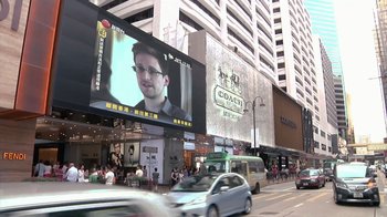 Movie still from “Citizenfour” (2014), directed by Laura Poitras – A large screen on the side of a building; Extreme Wide shot, Low angle