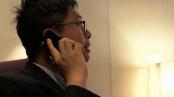 Movie still from “Citizenfour” (2014), directed by Laura Poitras – A man wearing glasses talking on a cell phone; Close Up shot, Over the shoulder angle