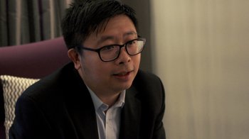 Movie still from “Citizenfour” (2014), directed by Laura Poitras – A man wearing glasses and a suit and tie; Close Up shot, Over the shoulder angle