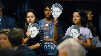 Movie still from “Citizenfour” (2014), directed by Laura Poitras – A group of young people holding up masks of snowden; Extreme Close Up shot, High angle