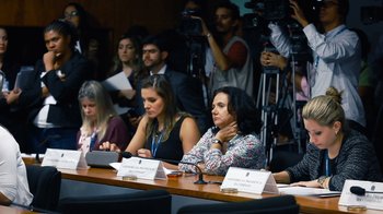 Movie still from “Citizenfour” (2014), directed by Laura Poitras – A group of people sitting at a table with microphones; Medium shot, Over the shoulder angle