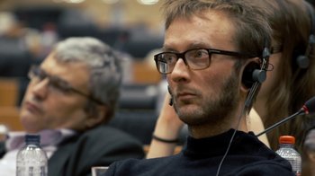 Movie still from “Citizenfour” (2014), directed by Laura Poitras – A man with glasses and a headset on; Close Up shot, High angle