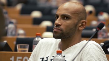 Movie still from “Citizenfour” (2014), directed by Laura Poitras – A man with a bald head sitting in a lecture hall; Close Up shot, Over the shoulder angle