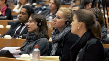Movie still from “Citizenfour” (2014), directed by Laura Poitras – A group of people sitting in a room with headphones on; Close Up shot, High angle