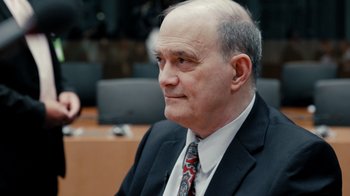 Movie still from “Citizenfour” (2014), directed by Laura Poitras – An older man wearing a suit and tie; Close Up shot, Over the shoulder angle