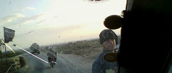 Movie still from “City of Ghosts” (2017), directed by Matthew Heineman – A man riding a motorcycle on the side of a road; Close Up shot, High angle
