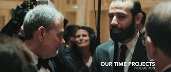 Movie still from “City of Ghosts” (2017), directed by Matthew Heineman – Two men in suits talking to each other; Medium shot, Over the shoulder angle