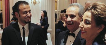 Movie still from “City of Ghosts” (2017), directed by Matthew Heineman – A man in a suit and tie standing next to another man in a tuxedo; Medium shot, Low angle