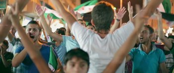Movie still from “City of Ghosts” (2017), directed by Matthew Heineman – A group of young people raising their hands in the air; Medium shot, Low angle