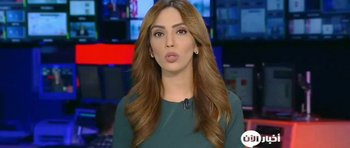 Movie still from “City of Ghosts” (2017), directed by Matthew Heineman – A woman in a green shirt is talking on a tv set; Close Up shot, Over the shoulder angle