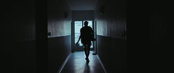 Movie still from “City of Ghosts” (2017), directed by Matthew Heineman – A person walking down a hallway with a bag; Wide shot, Low angle