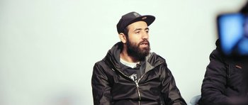 Movie still from “City of Ghosts” (2017), directed by Matthew Heineman – A man with a beard wearing a black jacket and a hat; Close Up shot, Low angle