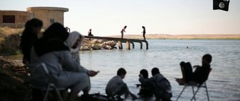 Movie still from “City of Ghosts” (2017), directed by Matthew Heineman – A group of people standing on a pier near a body of water; Extreme Wide shot, High angle