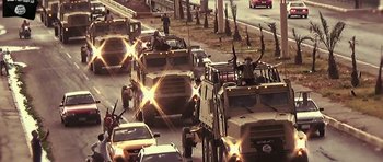 Movie still from “City of Ghosts” (2017), directed by Matthew Heineman – Military vehicles driving down a street in the middle of the day; Extreme Wide shot, High angle